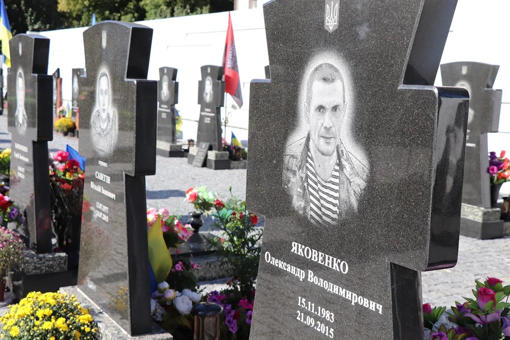Гранітний хрест на могилі Олександра Яковенка серед інших військових поховань
