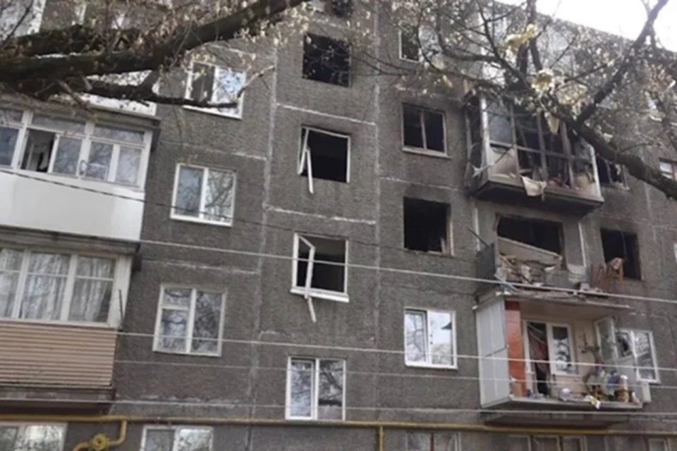 Пошкоджений сірий багатоквартирний будинок із вибитими вікнами та зруйнованими балконами