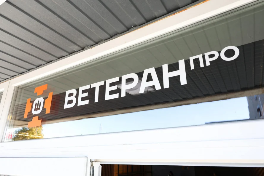 Скляна вивіска Veteran Про з помаранчевим логотипом і тризубом над входом