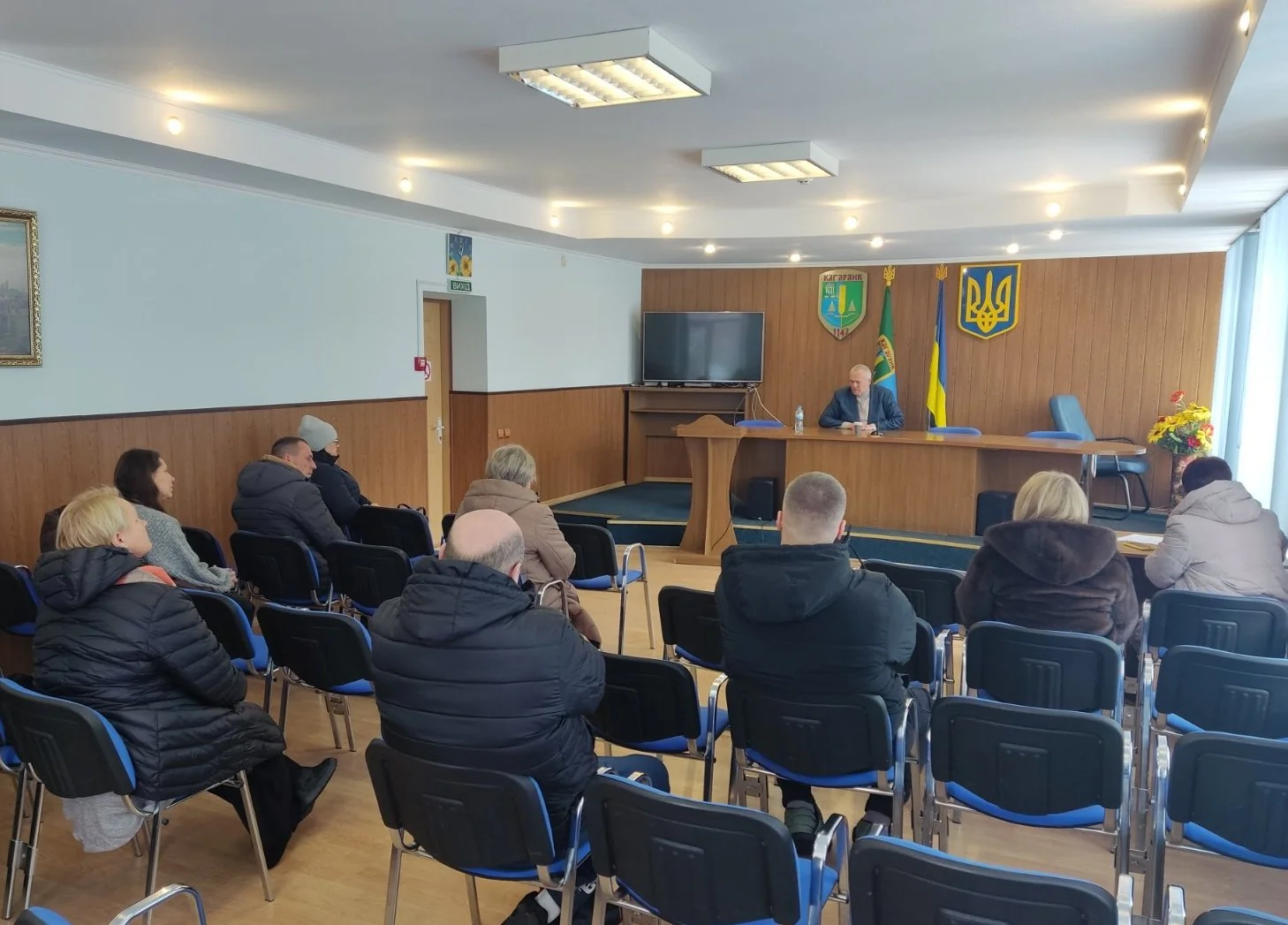 Люди на засіданні в залі Кагарлицької міськради з гербом і прапорами