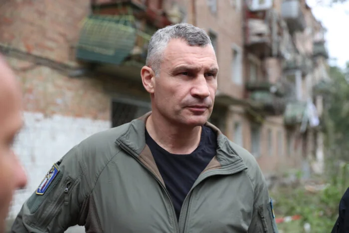 Віталій Кличко в оливковій куртці стоїть біля пошкодженої багатоповерхівки