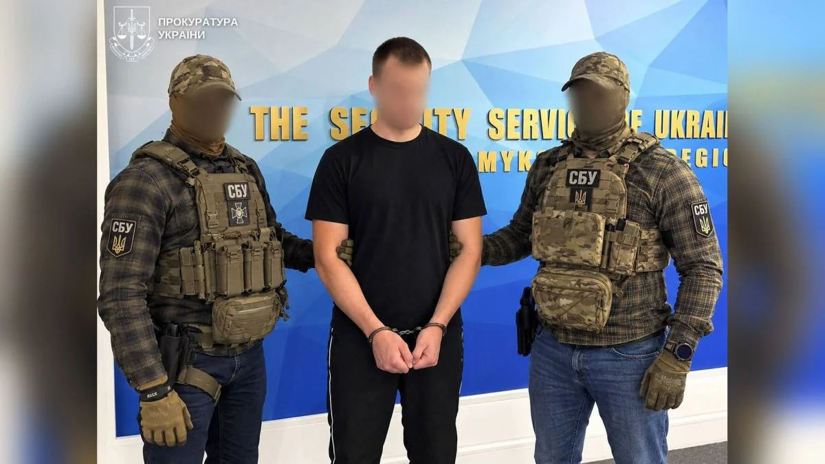 Співробітники СБУ з затриманим у наручниках на тлі банера СБУ Миколаївщини
