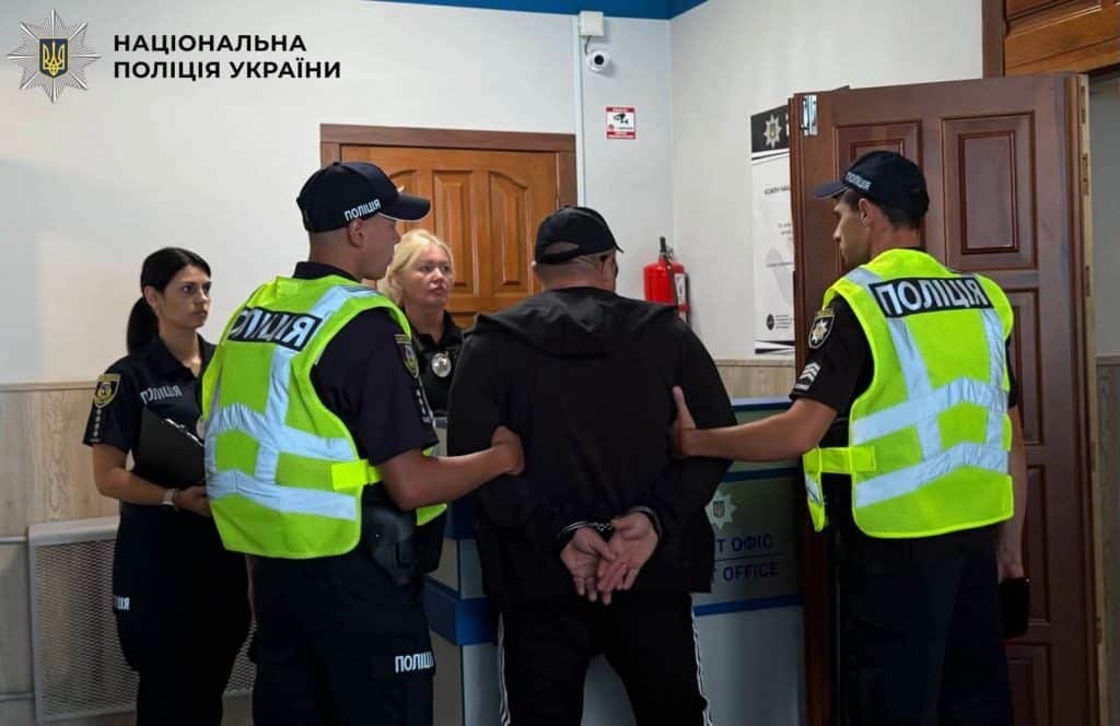Поліцейські супроводжують затриманого в наручниках у приміщенні відділку