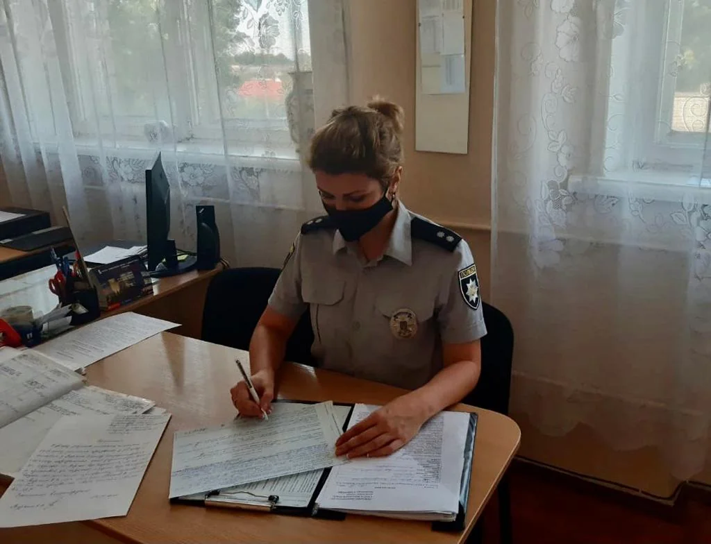 Поліцейська в формі та масці заповнює документи за столом
