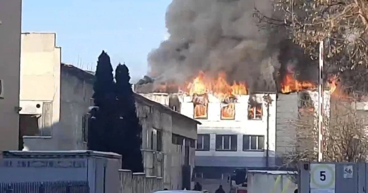 Пожежа на даху білої будівлі, полум’я у вікнах і густий чорний дим