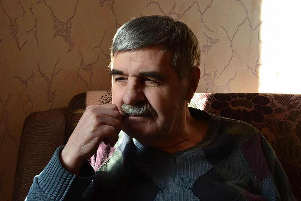 Літній чоловік із сивим волоссям і вусами сидить на дивані