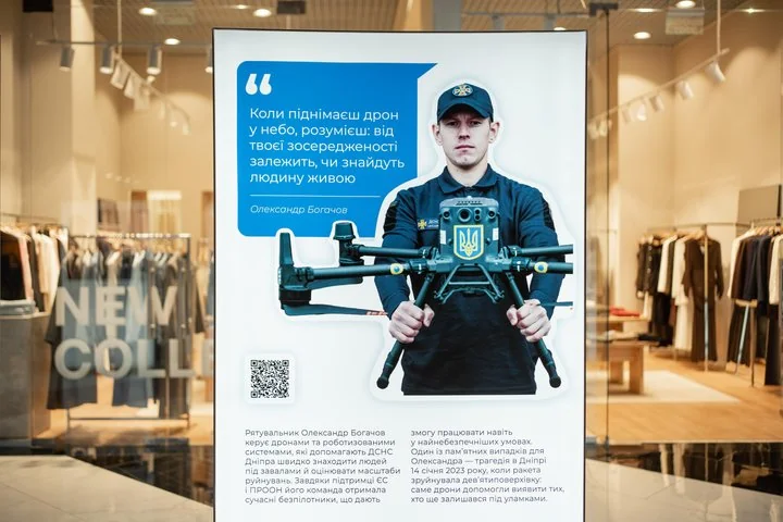 Плакат у вітрині магазину з рятувальником у формі, який тримає дрон