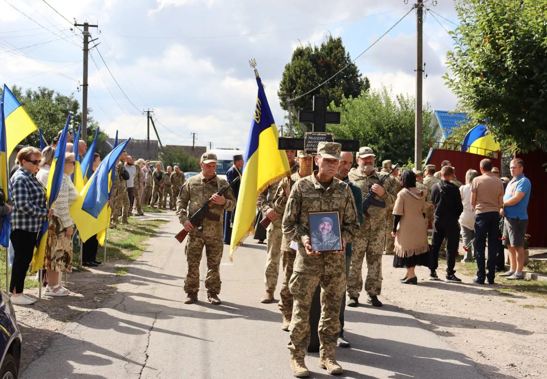 Військові з прапорами несуть портрет загиблого на сільській вулиці