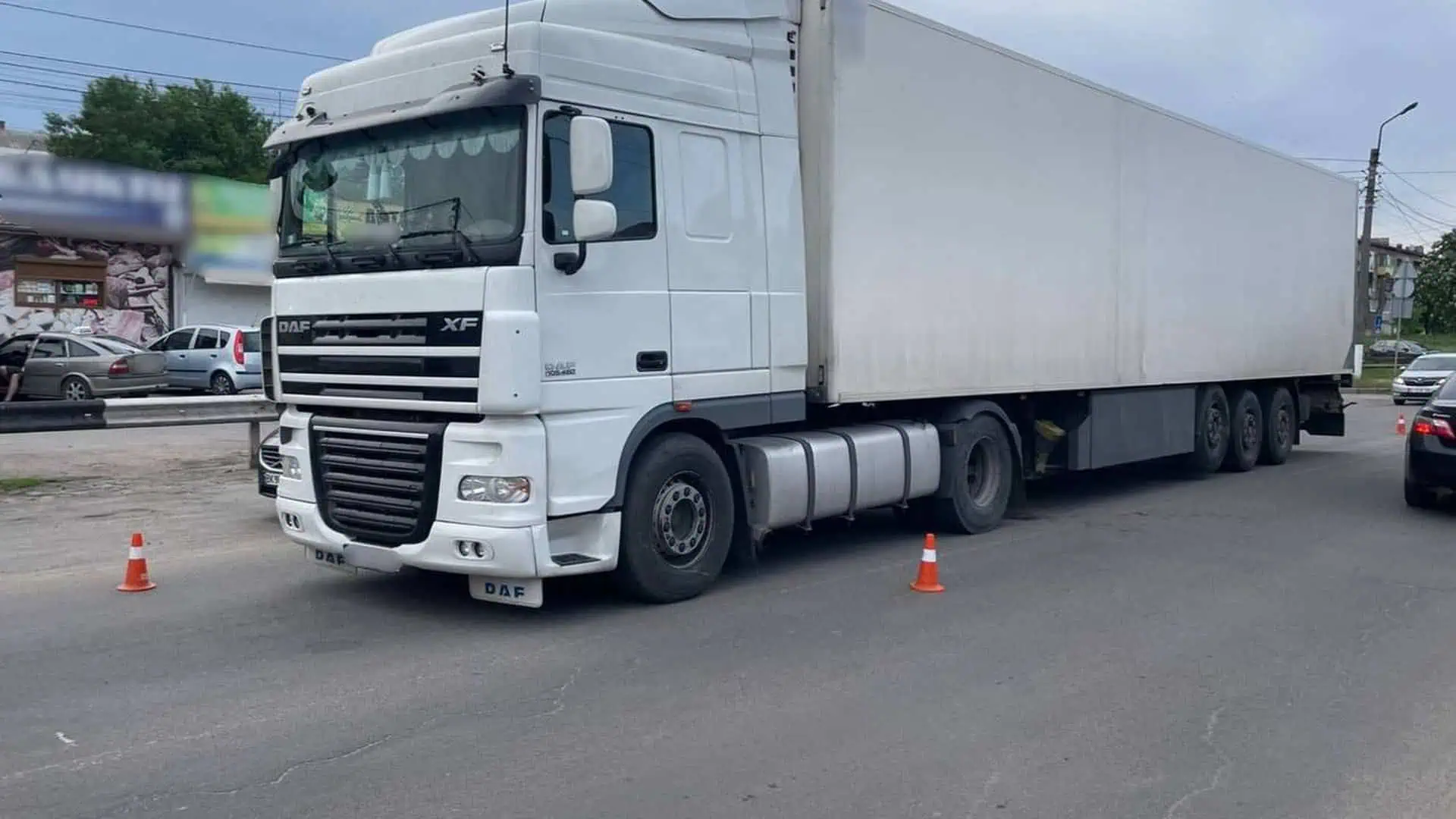 Біла фура DAF XF з причепом стоїть на дорозі біля оранжевих конусів