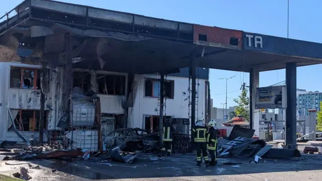 Пожежники біля згорілої АЗС з обвугленим навісом і уламками