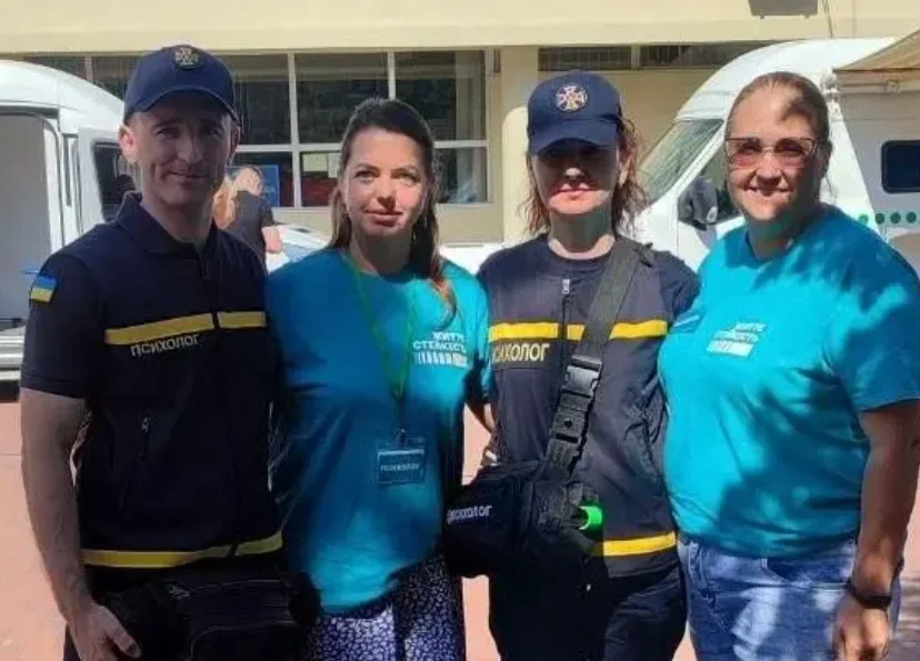 Чотири фахівці — психологи ДСНС і працівники центру життєстійкості — стоять разом біля білих мікроавтобусів