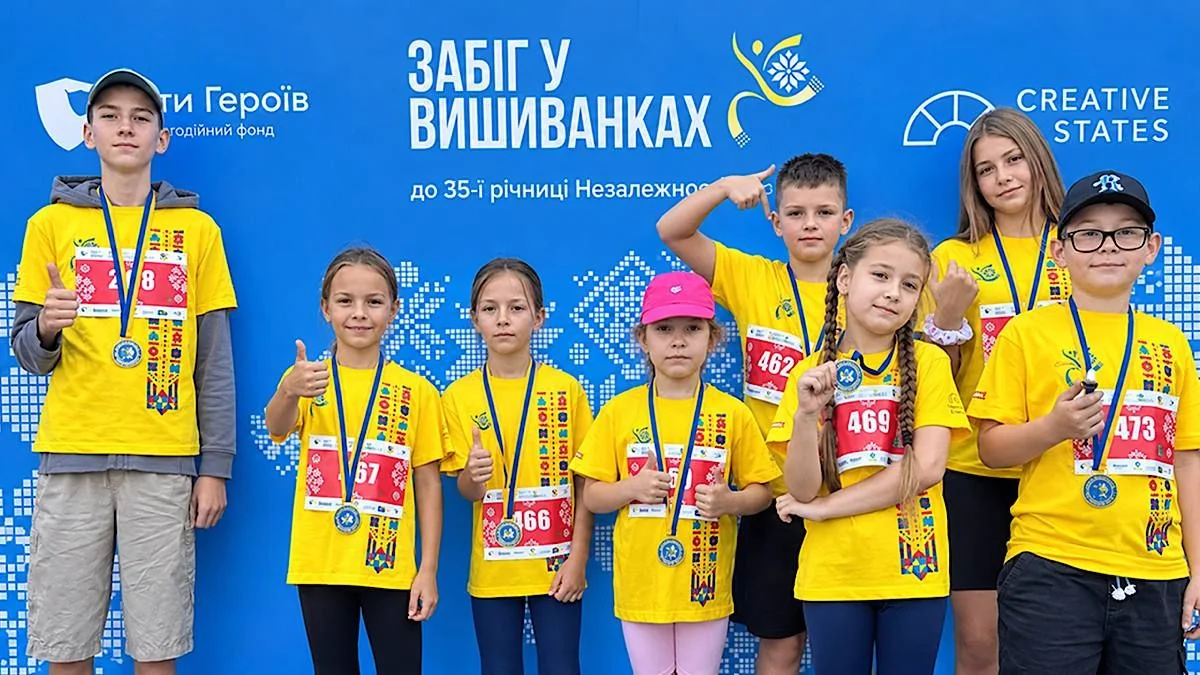 Діти в жовтих футболках з медалями біля банера Забігу у вишиванках